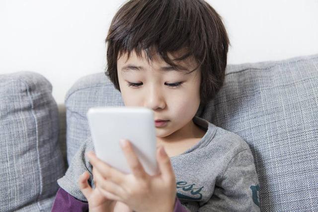 Dùng điện thoại thông minh trong nhiều tiếng đồng hồ mỗi ngày có nguy cơ làm giảm thị lực của trẻ. (Ảnh minh họa: Japan Times)